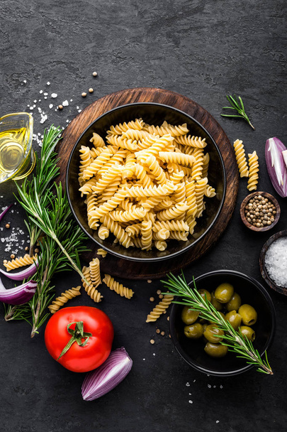 Pasta and ingredients for cooking on black background, top view. Italian food - 写真・画像