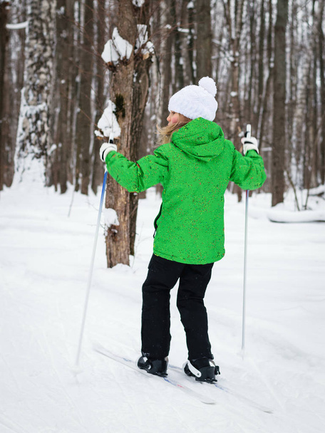 Φωτογραφία κορίτσια σε ένα πράσινο σακάκι σκι μέσα στο δάσος του χειμώνα. - Φωτογραφία, εικόνα