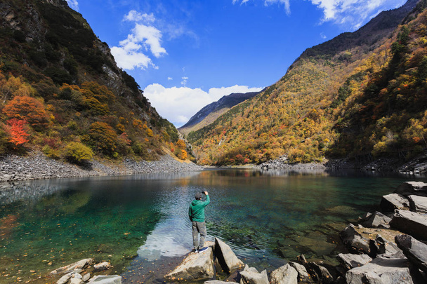 Ένας άνθρωπος στέκεται από τη λίμνη και τη λήψη φωτογραφιών - Φωτογραφία, εικόνα
