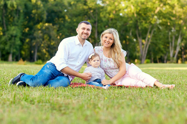 Happy family in a park in summer autumn. Mother, father and baby - Foto, afbeelding