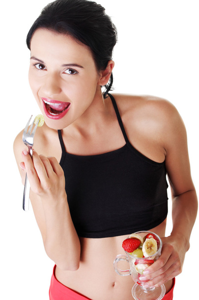 Pretty fit woman eating fruit salad - Foto, Bild