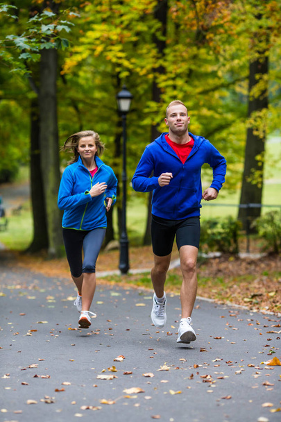 Healthy lifestyle - woman and man running in park - 写真・画像
