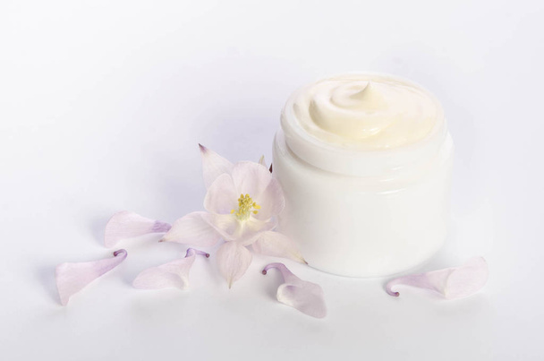 Linda flor y un frasco de crema corporal natural aislado en blanco
 - Foto, imagen