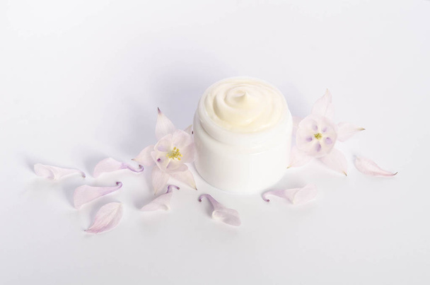 Cute flowers and petal and a jar of natural body cream - Foto, Imagem