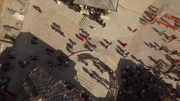 4k Menschenmassen bewegen sich auf dem alten europäischen Piazza-Zentrum von oben. Sonntags steht eine Gruppe von Gästen an der Kirchentreppe und grüßt und wartet darauf, dass eine Drohne abgeschossen wird. Leben einer mittelalterlichen Kleinstadt in Italien - Filmmaterial, Video