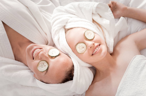 Happy nice mother and daughter doing a cucumber mask - Foto, imagen