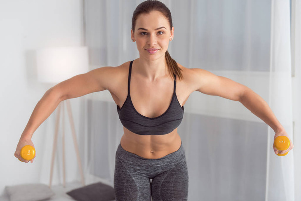 Alert woman using hand weights while exercising - Foto, Imagem