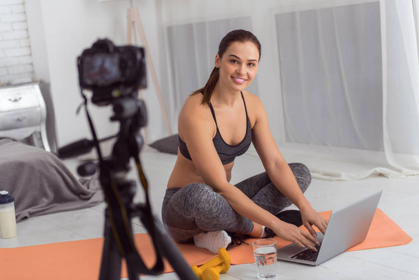 Content young woman using her laptop while exercising - Foto, imagen