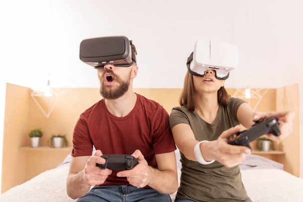 Young shocked couple playing in VR glasses - Valokuva, kuva