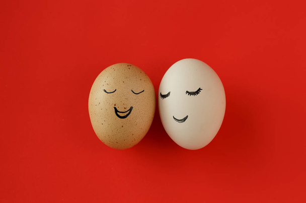 Dos huevos con una expresión alegre en el fondo rojo
 - Foto, Imagen