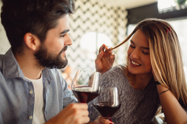 Γκρο πλαν, ένα όμορφο ρομαντικό ζευγάρι πόσιμο κόκκινο κρασί, ενώ για τον εορτασμό ημέρα του Αγίου Βαλεντίνου ή την επέτειό σας. - Φωτογραφία, εικόνα
