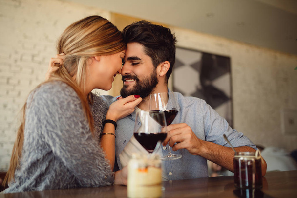 Közeli kép a gyönyörű romantikus pár, amelynek romantikus pillanatokat, ivott vörös bort, miközben Valentine's Day vagy évfordulóját ünnepli. - Fotó, kép