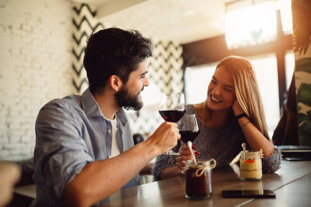 Portrait of a beautiful romantic couple drinking red wine while celebrating Valentine's Day in cafe. - Photo, Image