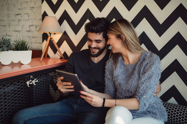 Giovane coppia seduta al internet cafè e rilassante sulla pausa caffè. Utilizzando tablet e wireless gratuito
. - Foto, immagini