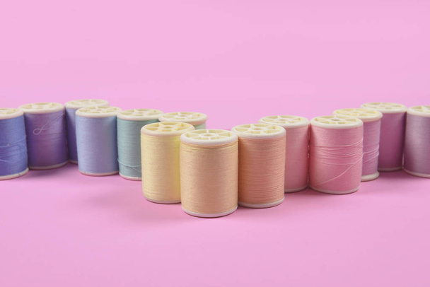 Flat lay of colored thread rolls for sewing on pink background,  - Zdjęcie, obraz