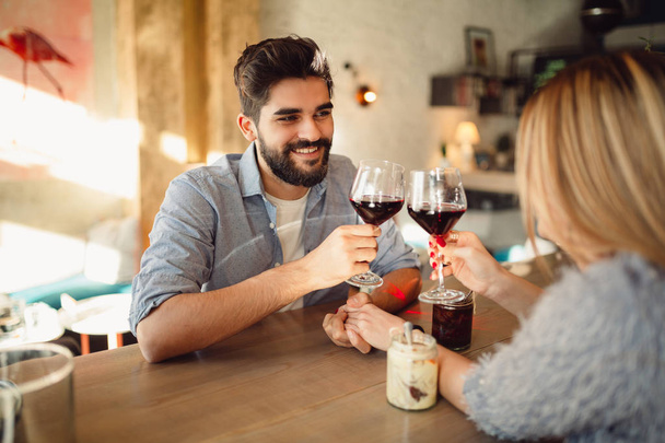 Romántica pareja clink vasos con vino tinto y la celebración del día de San Valentín o aniversario
. - Foto, imagen