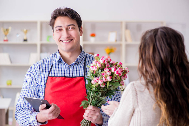 Asistente de floristería vendiendo flores a cliente femenino - Foto, Imagen