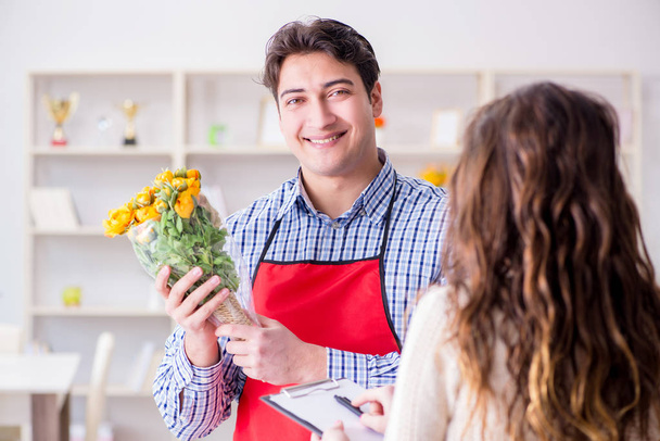 Asistente de floristería vendiendo flores a cliente femenino - Foto, imagen
