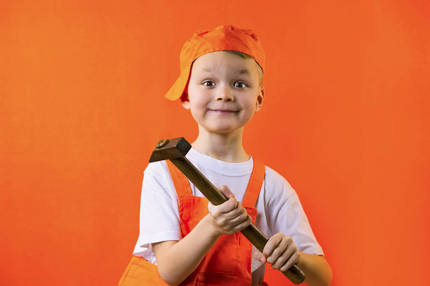 funny builder boy holding a hammer on an orange background - Фото, зображення