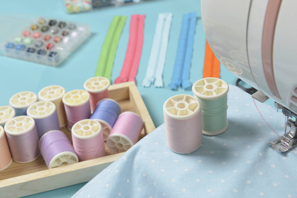 Fabrics on sewing machine amid the scissors, shirt buttons, zipp - Фото, изображение