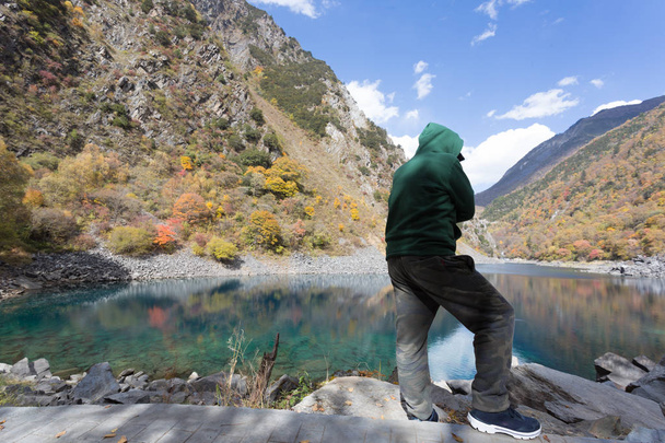 Ένας άνθρωπος που φοράει ένα πράσινο πουλόβερ στέκεται στην κοιλάδα κοίταξε προς τα κάτω - Φωτογραφία, εικόνα