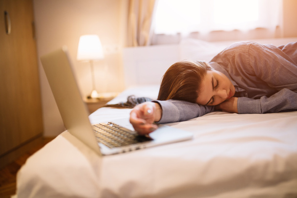 ノート パソコン近くに寝てパジャマで疲れている女の子。コピー スペース. - 写真・画像