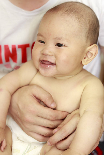 Un bébé riait joyeusement dans le bras de son père
 - Photo, image