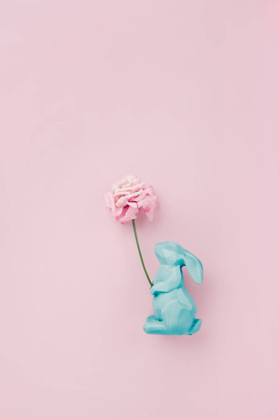Easter rabbit figurine with a pink flower, flatlay on pink backg - Photo, Image