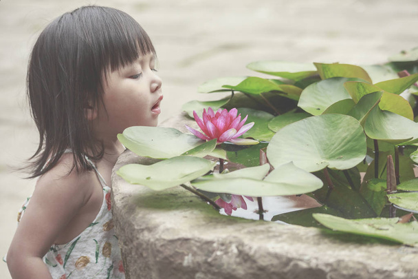 A little girl and a red water lily - Valokuva, kuva