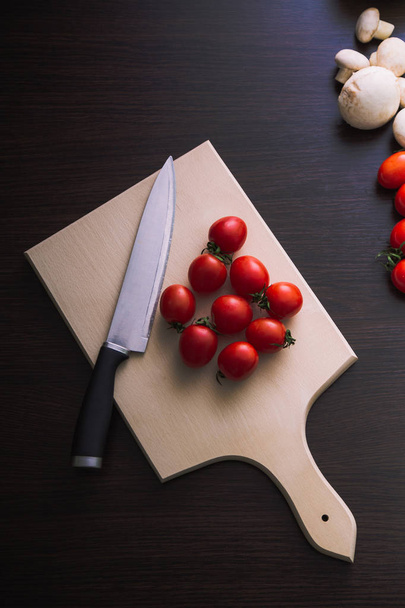 Vista superior de tomate cereja com faca na placa de madeira
. - Foto, Imagem