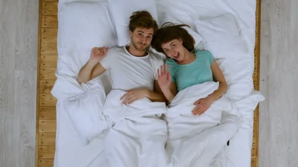 Happy couple in the bed. Showing good bye sign and fooling. - Filmagem, Vídeo