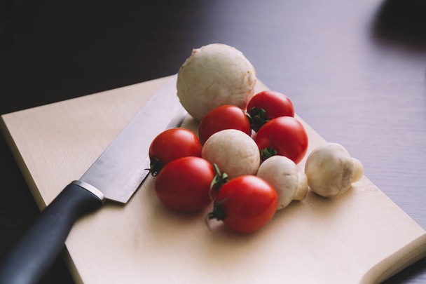 Zbliżenie z pomidorów cherry i grzyby na stół do cięcia drewna - Zdjęcie, obraz