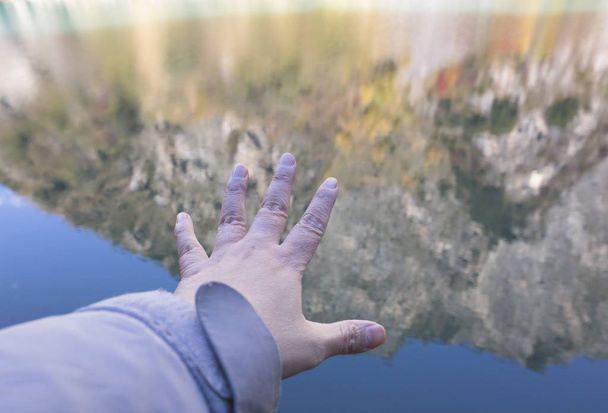 手が湖に伸び、水が反射した  - 写真・画像