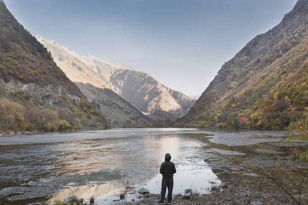 Un hombre vistiendo un suéter verde de pie en el valle miró hacia abajo
 - Foto, imagen