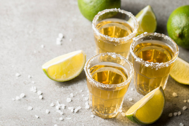 Makrofokus kuva laukausta kultainen meksikolainen tequila limetti ja suola puinen tausta. Alkoholijuoman käsite
. - Valokuva, kuva