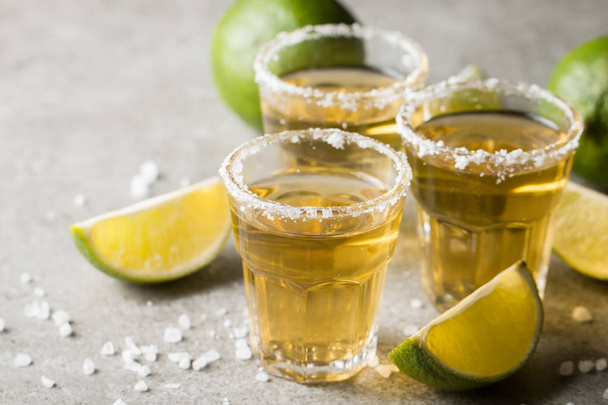 Macro focus photo of shots of golden Mexican tequila with lime and salt on wooden background. Alcoholic drink concept. - 写真・画像