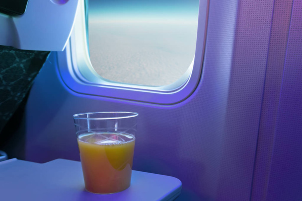 A cup of orange juice on tray at cabin seat of an aircraft. - Photo, Image