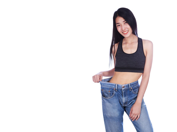 女性は彼女の減量と身に着けている彼女の古いジーンズ分離 o を示しています - 写真・画像