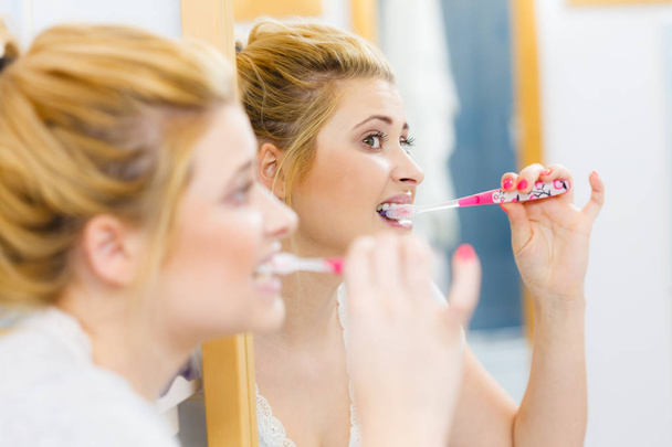 Woman brushing cleaning teeth in bathroom - Фото, изображение