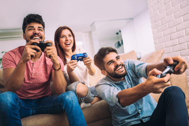 Grupo de jóvenes amigos juegan videojuegos juntos en casa
. - Foto, Imagen