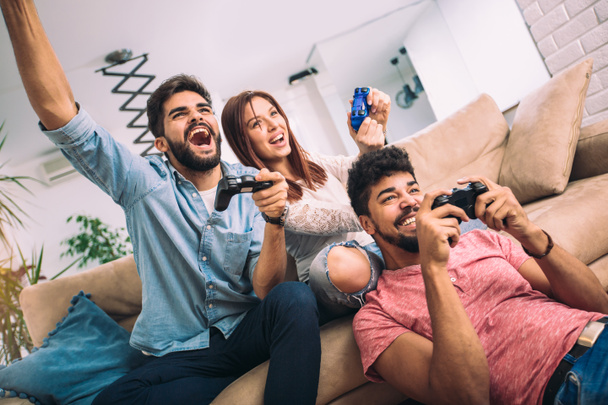 Група молодих друзів грають у відеоігри вдома
. - Фото, зображення