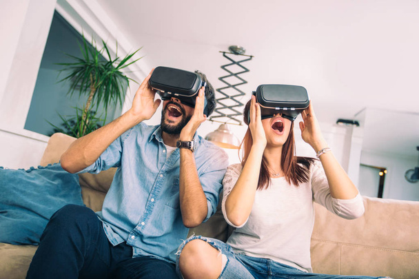 Νεαρός άνδρας και γυναίκα στο casual ρούχα φορούν τα γυαλιά εικονικής πραγματικότητας βλέποντας και δείχνοντας φανταστείτε μέσω της έννοιας Vr φωτογραφικών μηχανών, τεχνολογίας και καινοτομίας - Φωτογραφία, εικόνα