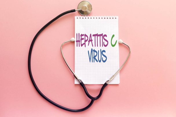 betegség Hepatitis koncepció kézírás fehér notebook és sztetoszkóp, rózsaszín háttér - Fotó, kép