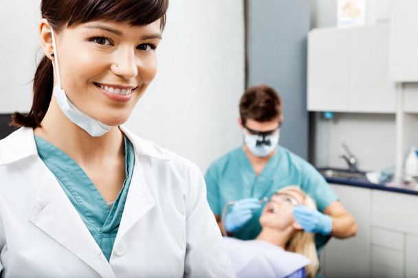 Female Hygienist With Dentist Working In The Background - Foto, immagini