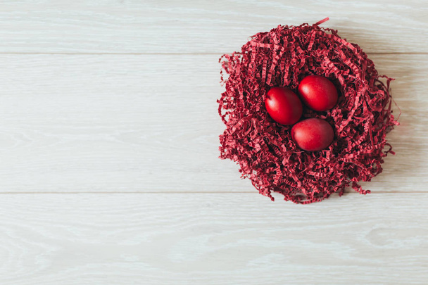 Red easter egg in the nest on wood background with space. - Photo, image