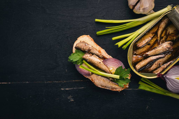 Sandwich with sprats, onions and parsley, on a wooden background. Top view. Copy space. - Фото, изображение