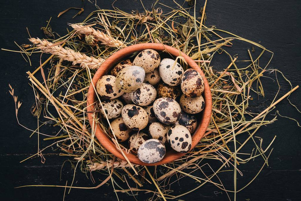 Quail eggs in a wooden bowl. On a wooden background. Top view. Copy space. - Foto, afbeelding