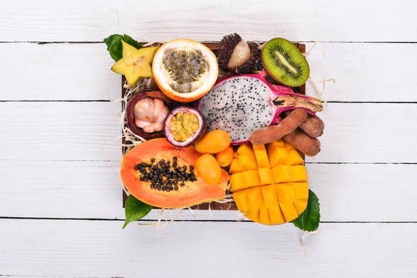 Fruit dragon, papaya, maracuya, kiwi, mango and granadilla in a wooden box. Fresh Tropical Fruits. On a wooden background. Top view. Copy space. - Фото, изображение