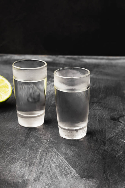 Cold vodka in shot glasses on a black background - Фото, изображение