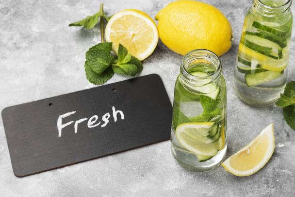 Bebida desintoxicante con pepino, limón y menta sobre un fondo gris
 - Foto, Imagen